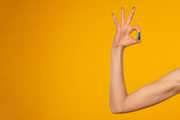 woman hand shows ok on yellow background