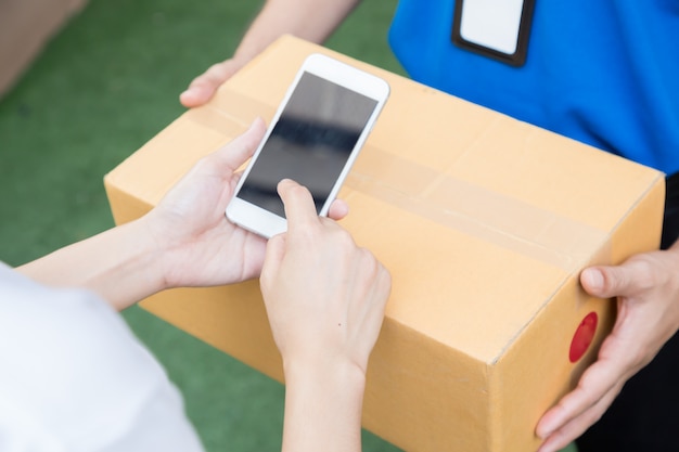 Рука женщины, подписывающая в мобильном телефоне с принятием доставки коробок от доставщика