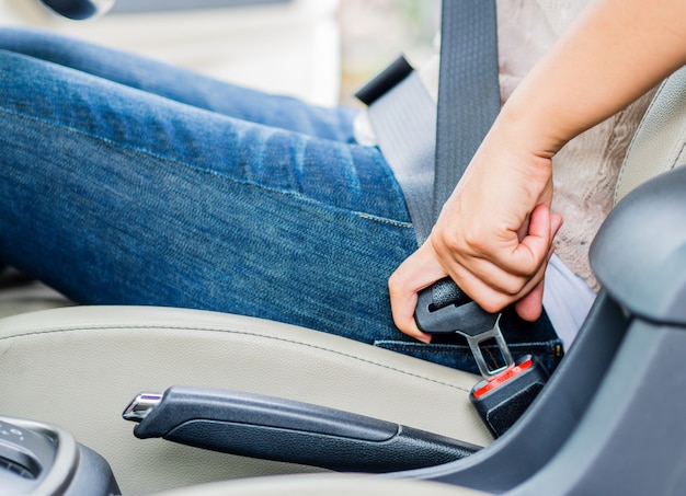 シートベルトを締めている車の中に座っている女性の手。まず安全ベルトの安全性を確認してください。