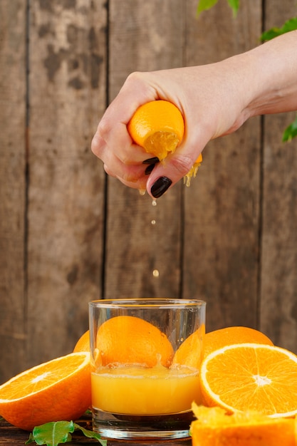 Woman hand squeezes orange juice close up