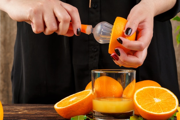 女性の手がオレンジジュースを絞る