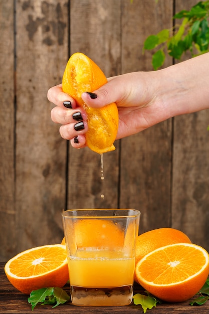 Woman hand squeezes orange juice close up