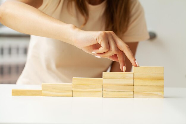 Woman hand stacking wooden blocks in shape of staircase