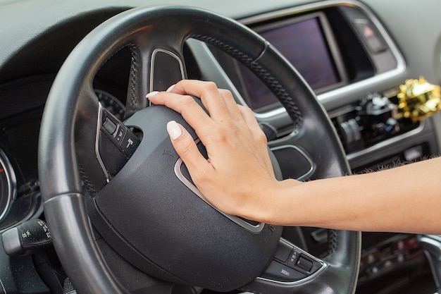 Woman hand on a steering wheel and honking a horn with her right hand.