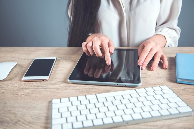 オフィスの机の上の女性の手のタブレット