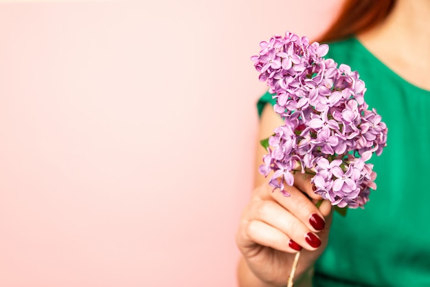 Woman hand take a purpure bouquet lilac flowers over colorful pink