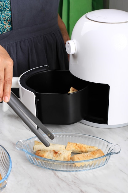 Woman Hand Taking Lumpia Out of Airfryer, Making Homemade Crispy Sweet Lumpia with Airfryer, Healthy Stule Snack without No Oil. Electric Kitchen Gadget for Non Fat Diet