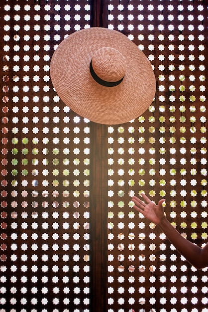 Mano di donna che lancia un cappello in uno sfondo geometrico