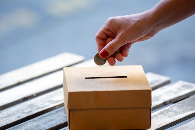 Woman hand throwing metal money into paper bank