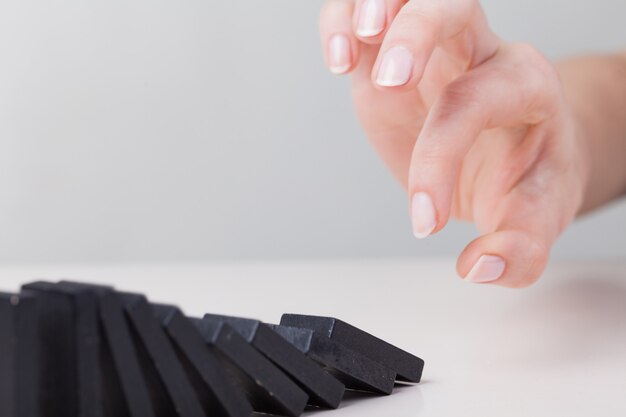 Woman hand toppling dominoes. chain reaction business concept Premium Photo