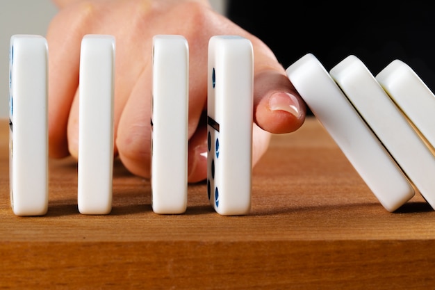 Woman hand toppling dominoes