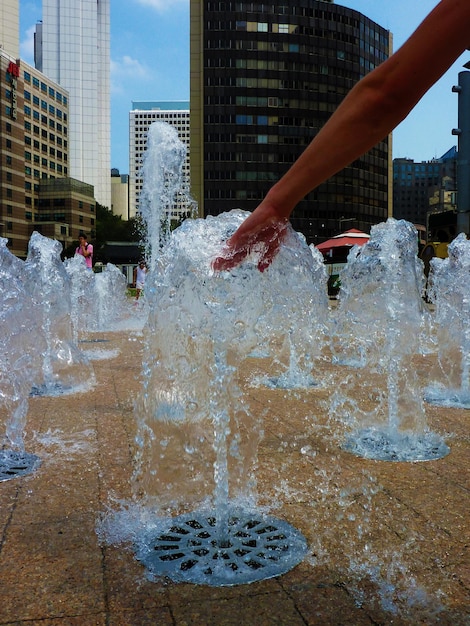 Photo woman hand touching water of fountain in city