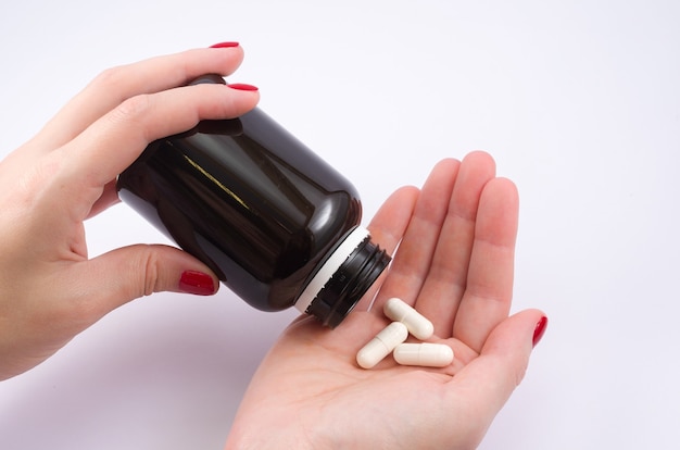 Woman hand turning medicine bottle in the palm of the hand. Doctor's prescription.