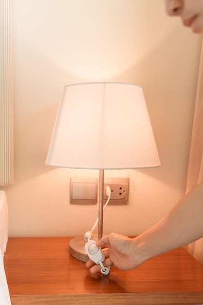 Женская рука включает или выключает минимальную лампу в современной спальне Концепция жизни в квартире