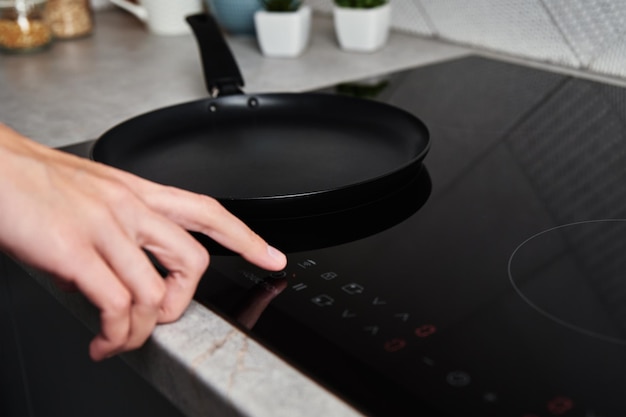 Photo woman hand turns on modern induction stove in the kitchen