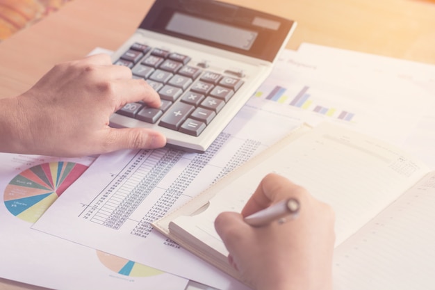 Woman hand using calculator and writing make note with calculate