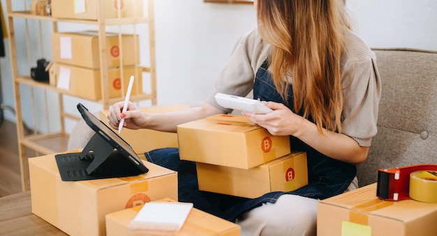 Woman hand using a laptop smartphone and tablet and writing notebook at the office of her business online shopping In home