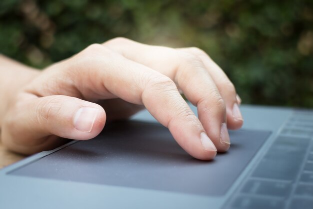 Foto mano della donna che per mezzo del touchpad del computer portatile