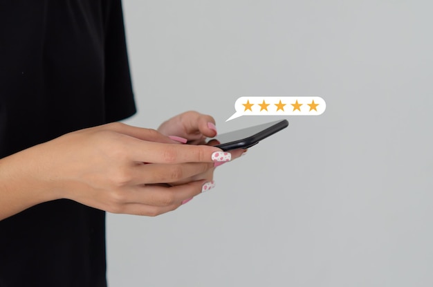 Mano della donna che utilizza lo smartphone mobile con l'icona a cinque stelle esperienza di servizio clienti feedback recensione soddisfazione