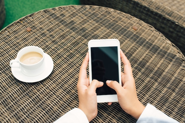 Woman hand using phone black screen on top view at coffe shop