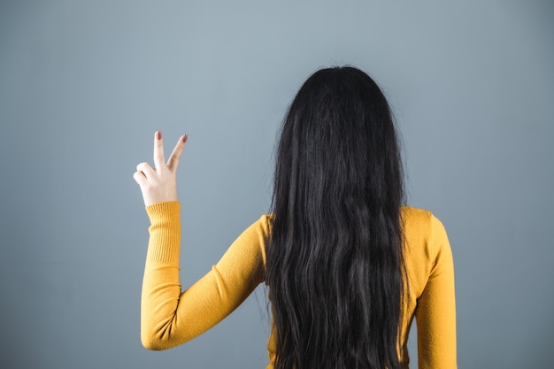 Woman hand victory sign on grey background