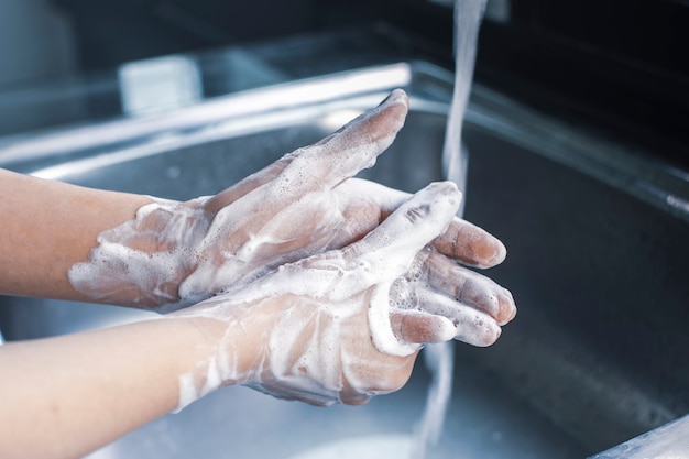 Женщина мыть руки с антибактериальным мылом против инфекционных микробов и коронавируса