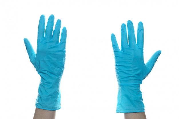 Woman hand  wearing a blue rubber medical glove on white isolated wall