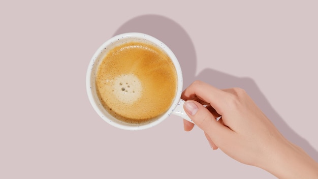 Woman hand and white coffee cup on pink background