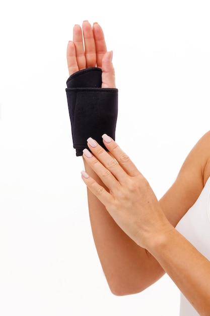 Фото Рука женщины с расчалкой запястья и пальца, ортопедическим оборудованием над белизной. вертикальное фото