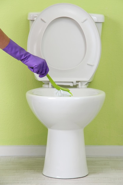 Woman hand with brush cleaning a toilet bowl in a bathroom