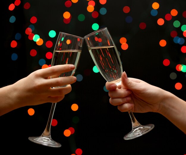 Woman hand with glasses of champagne, on garland background