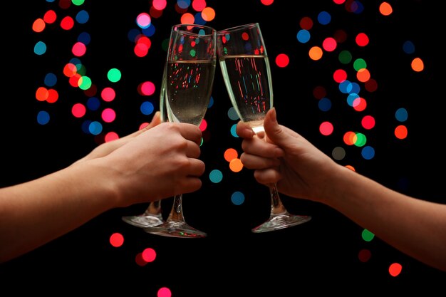 Woman hand with glasses of champagne, on garland background