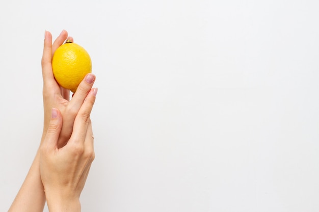 Woman hand with half of fresh lemon, free space for text