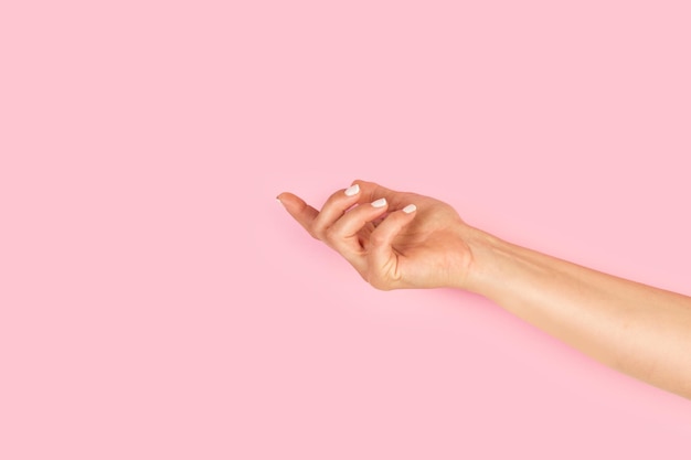 Женская рука с удерживающим жестом на розовом фоне с копировальным пространством
