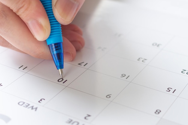 Женская рука с ручкой, пишущая на календарной дате, бизнес-планирование, назначение встречи, концепция