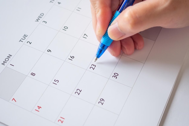 Woman hand with pen writing on calendar date business planning
appointment meeting concept