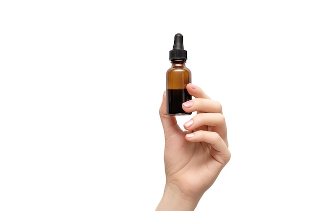 Woman hand with pink manicure. Female holding essential oil bottle isolated on white background. Female healthcare wellness concept.