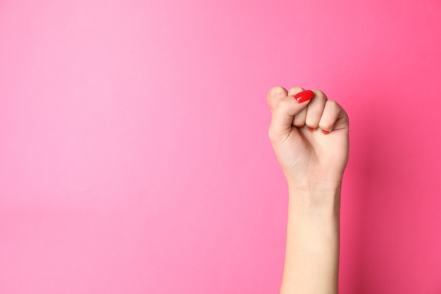 Woman hand with red nails on pink, space for text