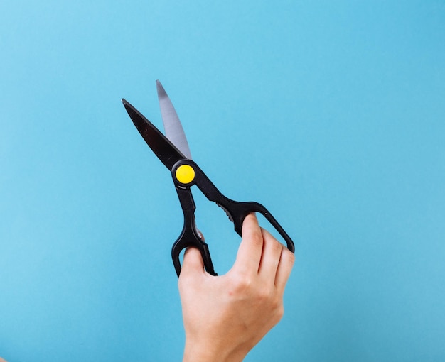 Woman hand with scissors. Isolated on blue.