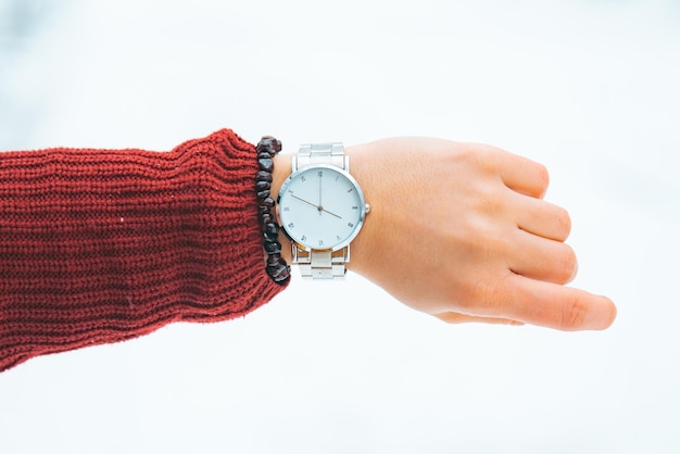 Woman hand with watch on wrist winter snowed park on background
