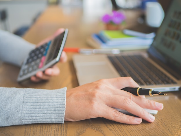 Woman hand working on her laptop with calculator. Social networking technology concept.