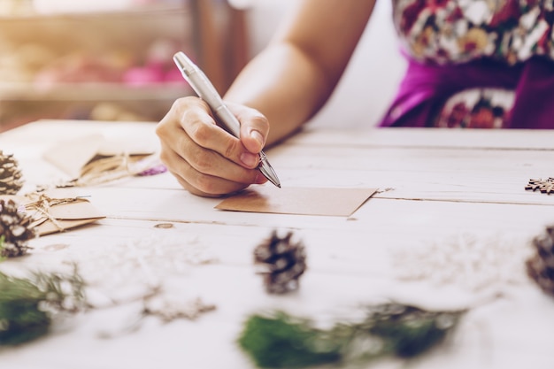 Woman hand writing beautiful Christmas card at table