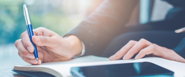 Foto mano della donna che scrive su un blocco note con una penna in ufficio