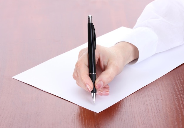 Woman hand writing on paper on wooden table