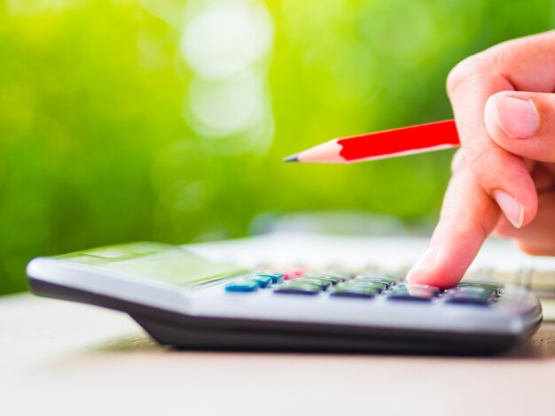 Woman hand writing with red pencil, business document and note book on working table 