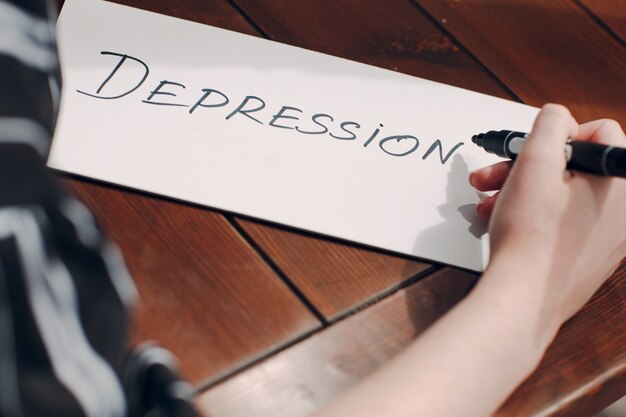 Foto donna mano scrittura parola depressione sul foglio bianco.