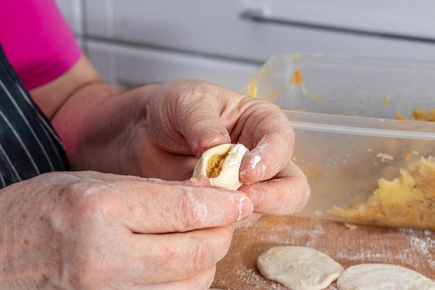 woman hands are making a damp dumpling On the wooden counter top are some raw