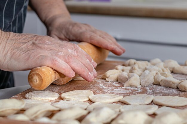 woman hands are making a damp dumpling On the wooden counter top are some raw