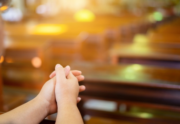Женские руки поклоняются христианскому богу, находясь в церкви.