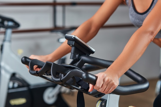 Woman hands on a bar stationary bike the gym